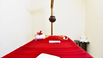Una stanza spa con un lettino da massaggio rosso, un utensile di legno per massaggi e asciugamani.