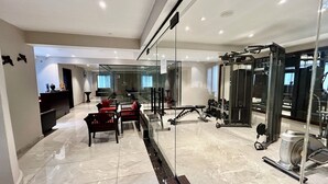A modern home gym with a glass wall, a treadmill, and various weights.