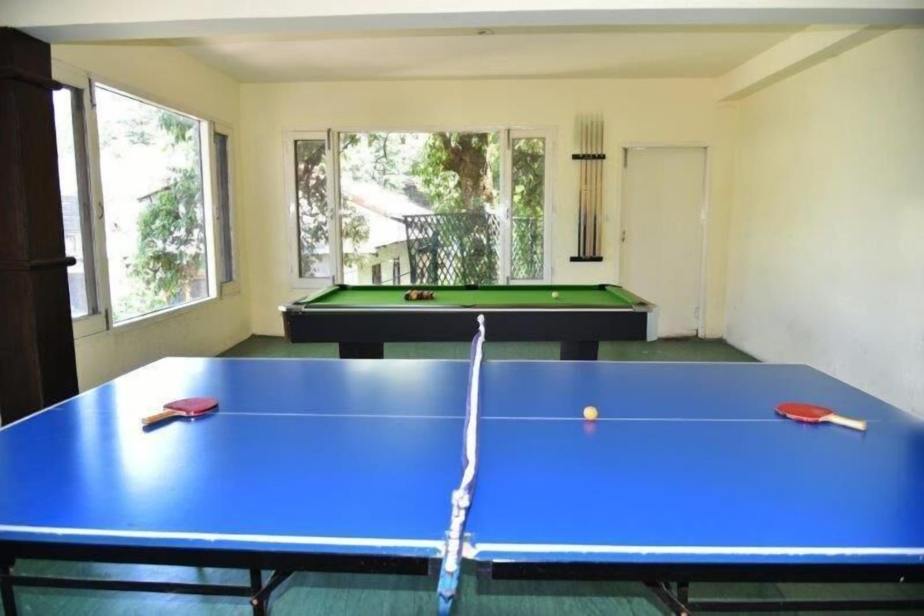 A room with a blue ping pong table, a pool table, and a door.