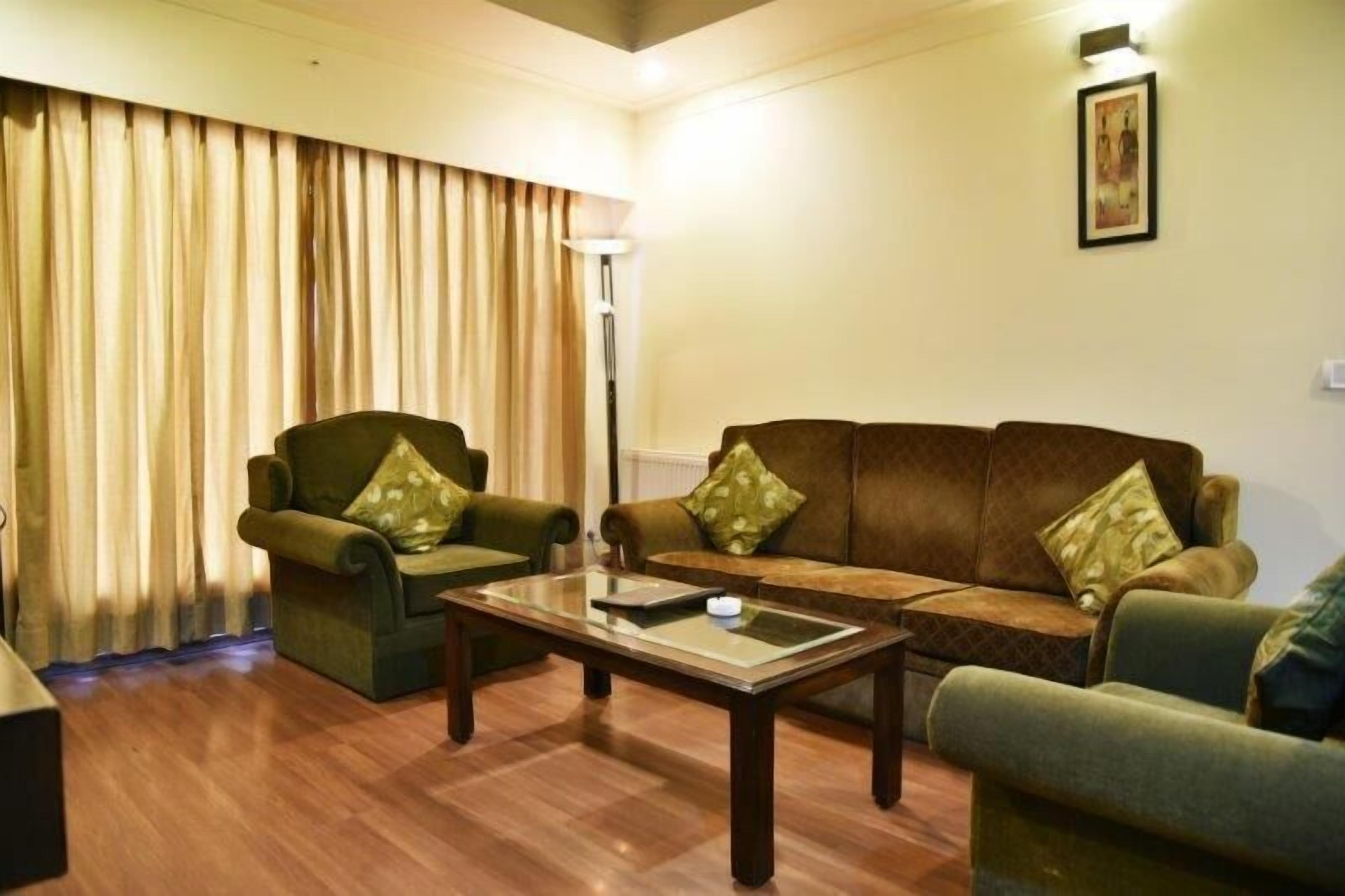 Una sala de estar con un sofá, dos sillones, una mesa de centro y una lámpara de pie.