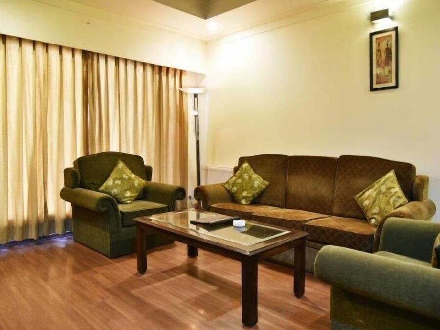 Una sala de estar con un sofá, dos sillones, una mesa de centro y una lámpara de pie.