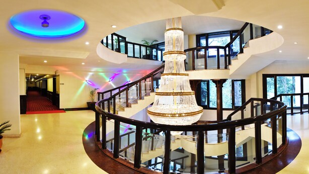 A multi-level interior with a central spiral staircase, glass railings, and a chandelier.