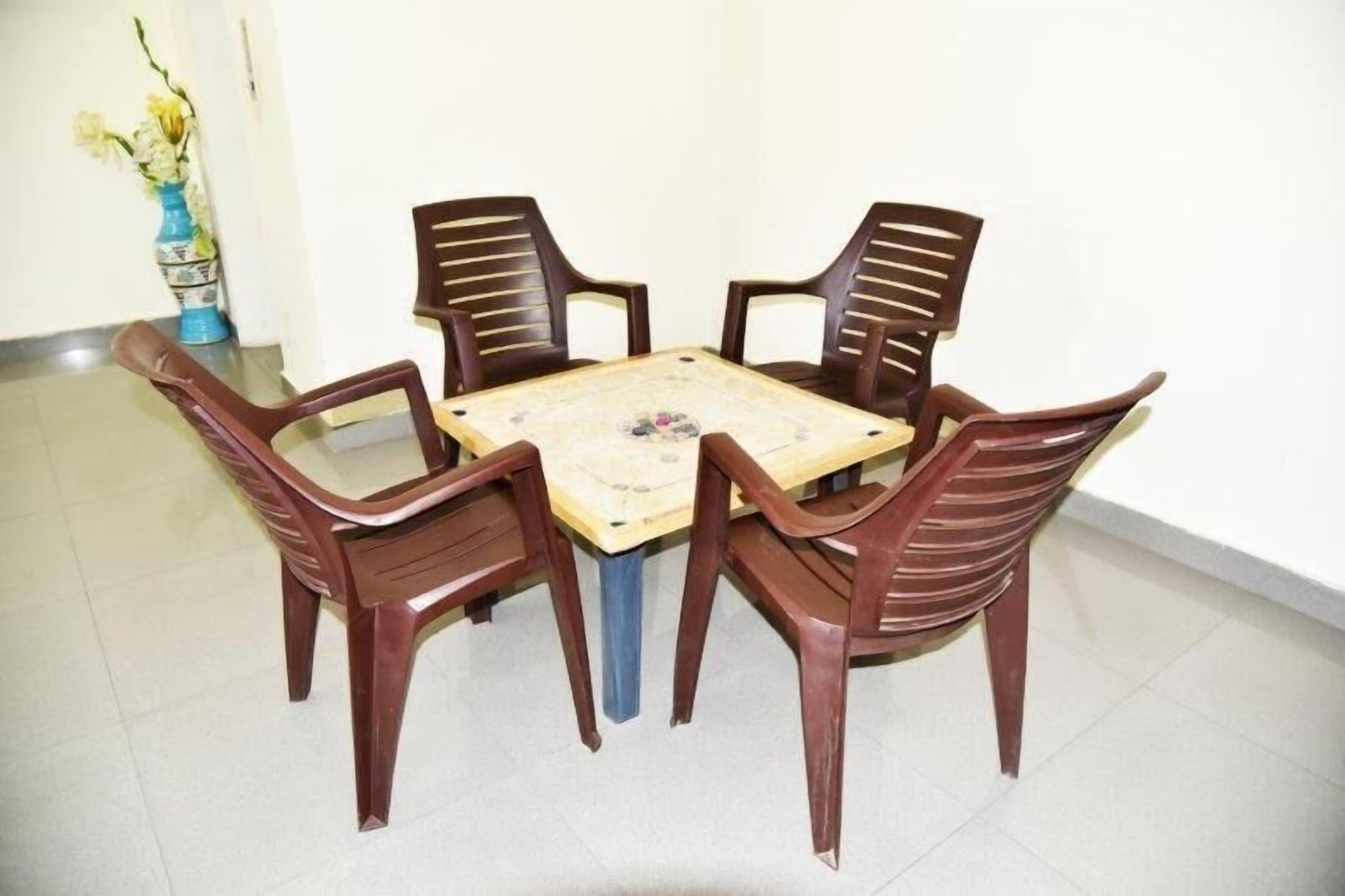 Uma mesa de jantar com quatro cadeiras, um vaso de flores e um chão em mosaico.