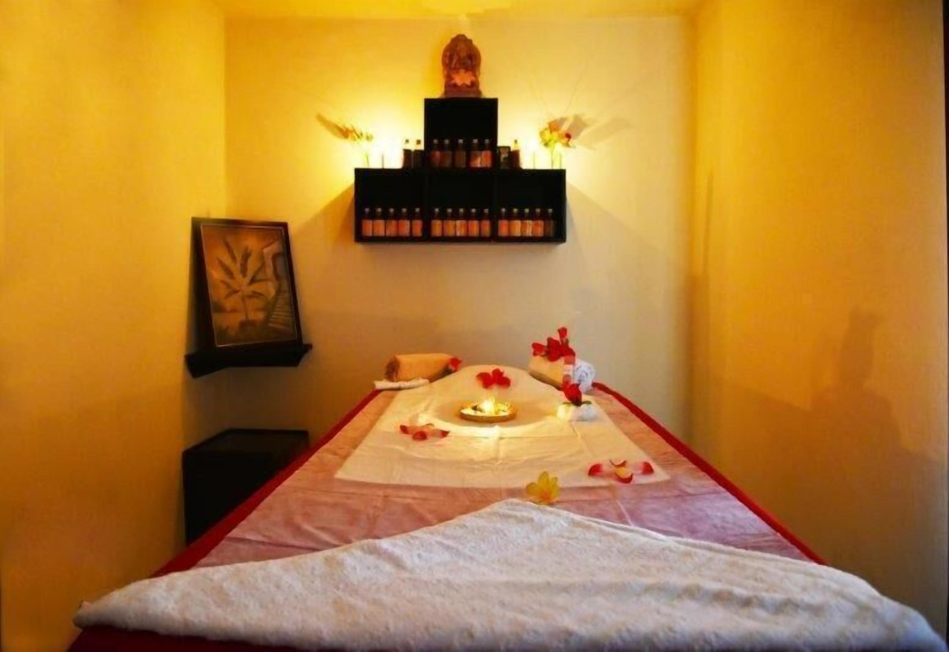 Una habitación con una cama, un estante con velas y un cuadro en la pared.