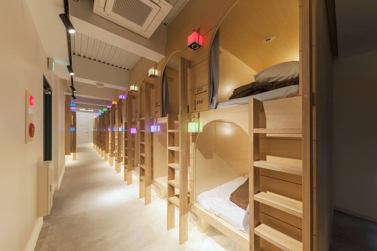 A hotel corridor with bunk beds, each labeled with a number, and a staircase leading to the upper level.