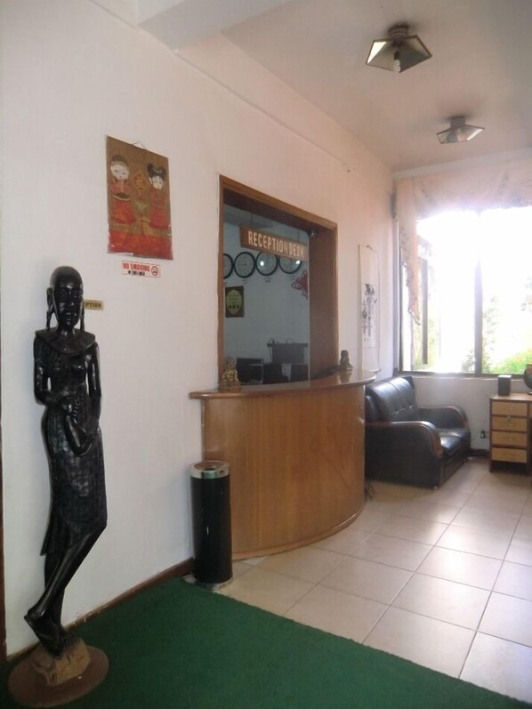 Un mostrador de recepción con un reloj, una estatua y un cartel de 'No Fumar'.