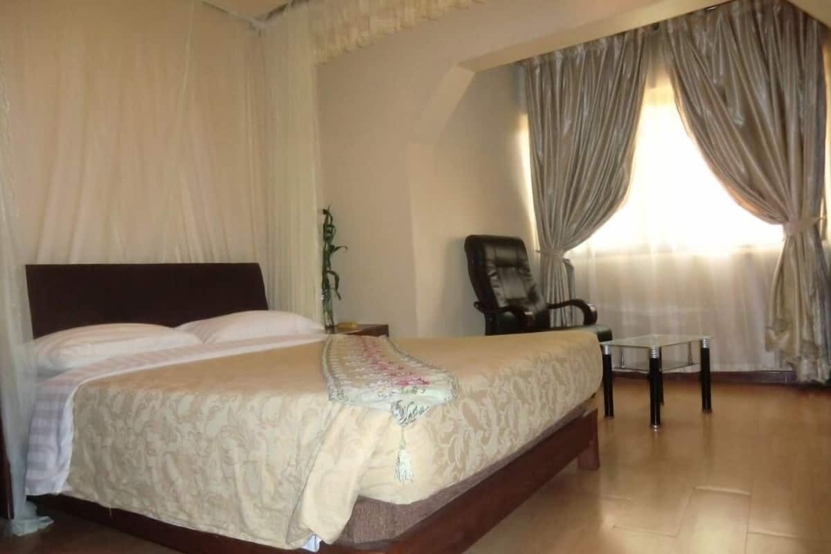A bedroom with a large bed, a chair, and a table.