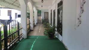A covered corridor with green carpet, white walls, and decorative ceiling. - Fang Fang Hotel (Kampala)