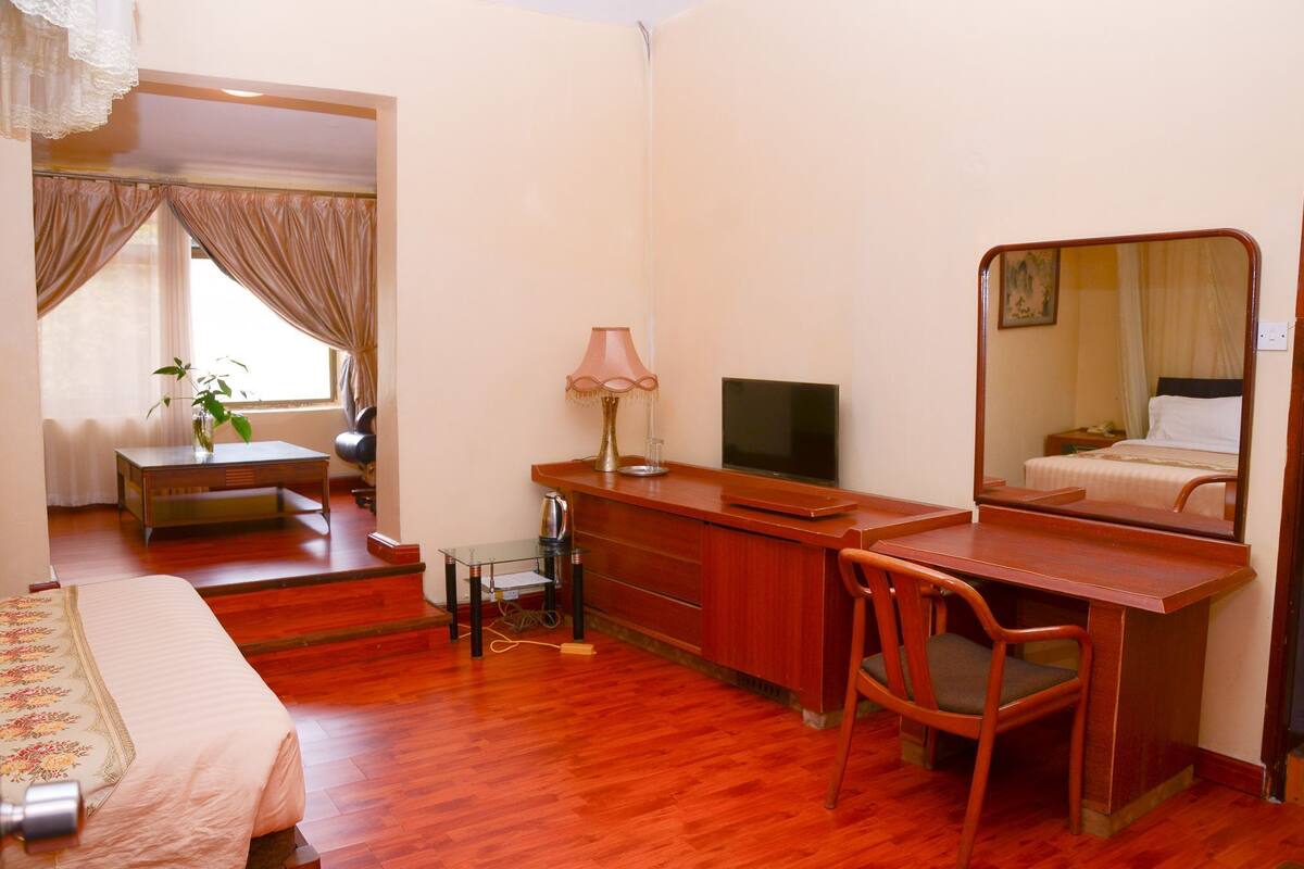 A hotel room with a bed, desk, chair, television, and a mirror.