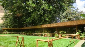A grassy area with wooden barriers and a building with 'FANG FANG' signage. - Fang Fang Hotel (Kampala)