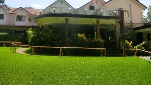 A building with a covered outdoor area, surrounded by greenery and a well-maintained lawn. - Fang Fang Hotel (Kampala)