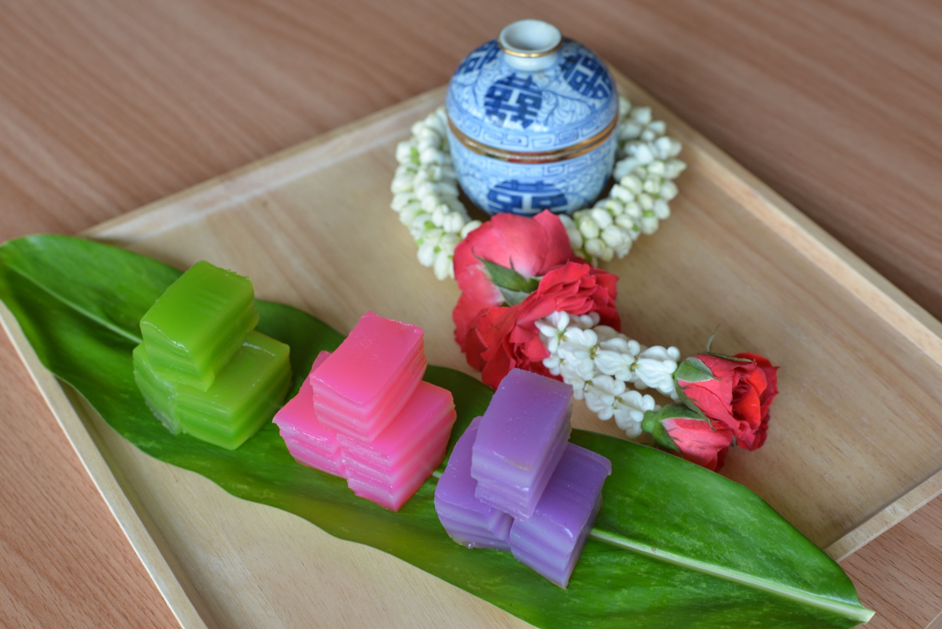 A wooden tray with colorful jelly cubes, a decorative vase, and flowers.