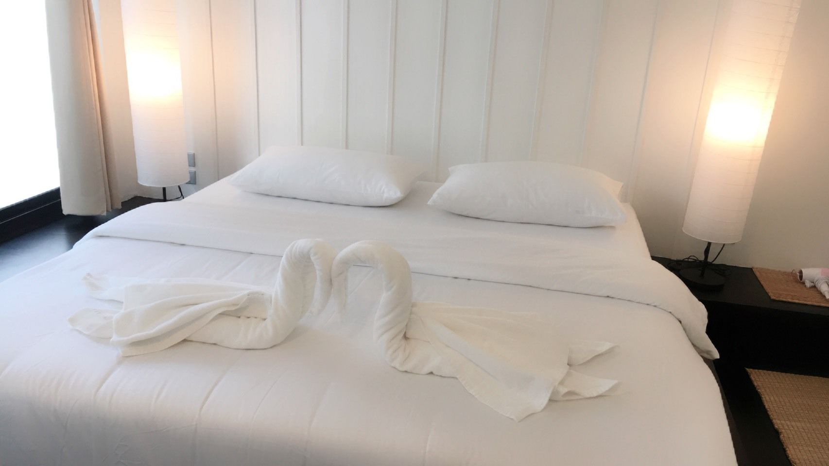 Una habitación de hotel con una cama bien hecha, dos almohadas y una decoración de toalla con forma de cisne.