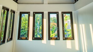 A room with a high ceiling, a sloped roof, and multiple windows. - Trat 101 Hotel (Trat)