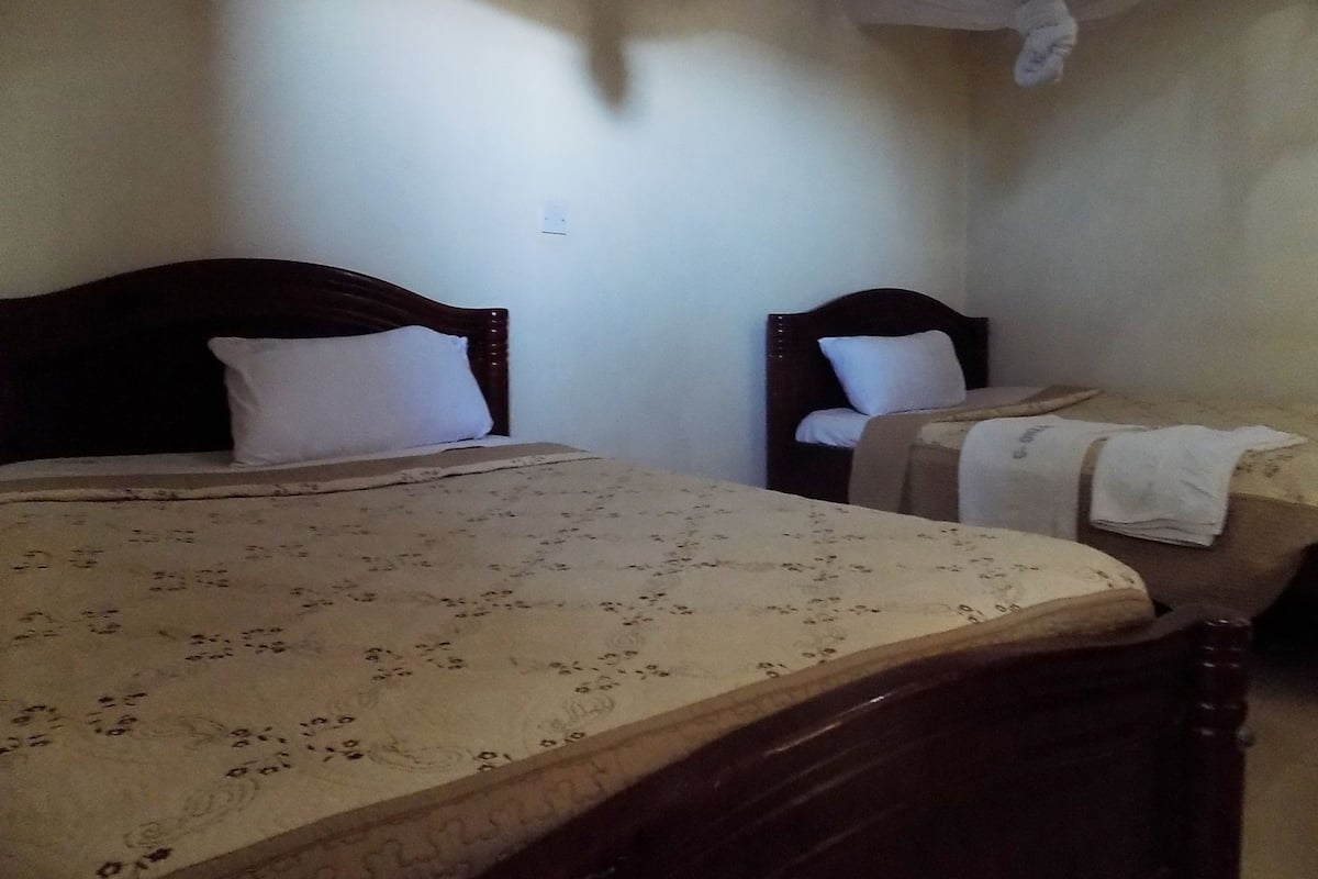 A room with two beds, each with a wooden headboard and white pillows.