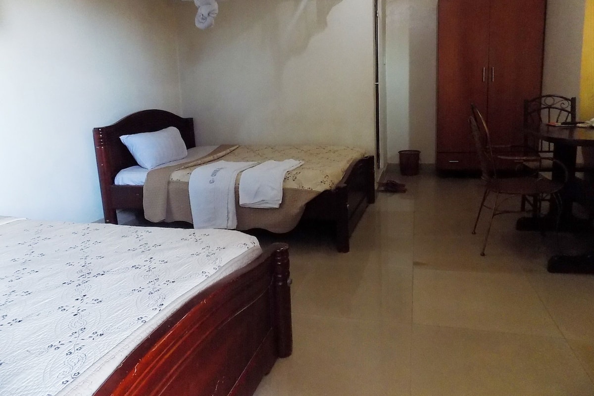 A bedroom with a bed, a chair, a table, and a wardrobe.