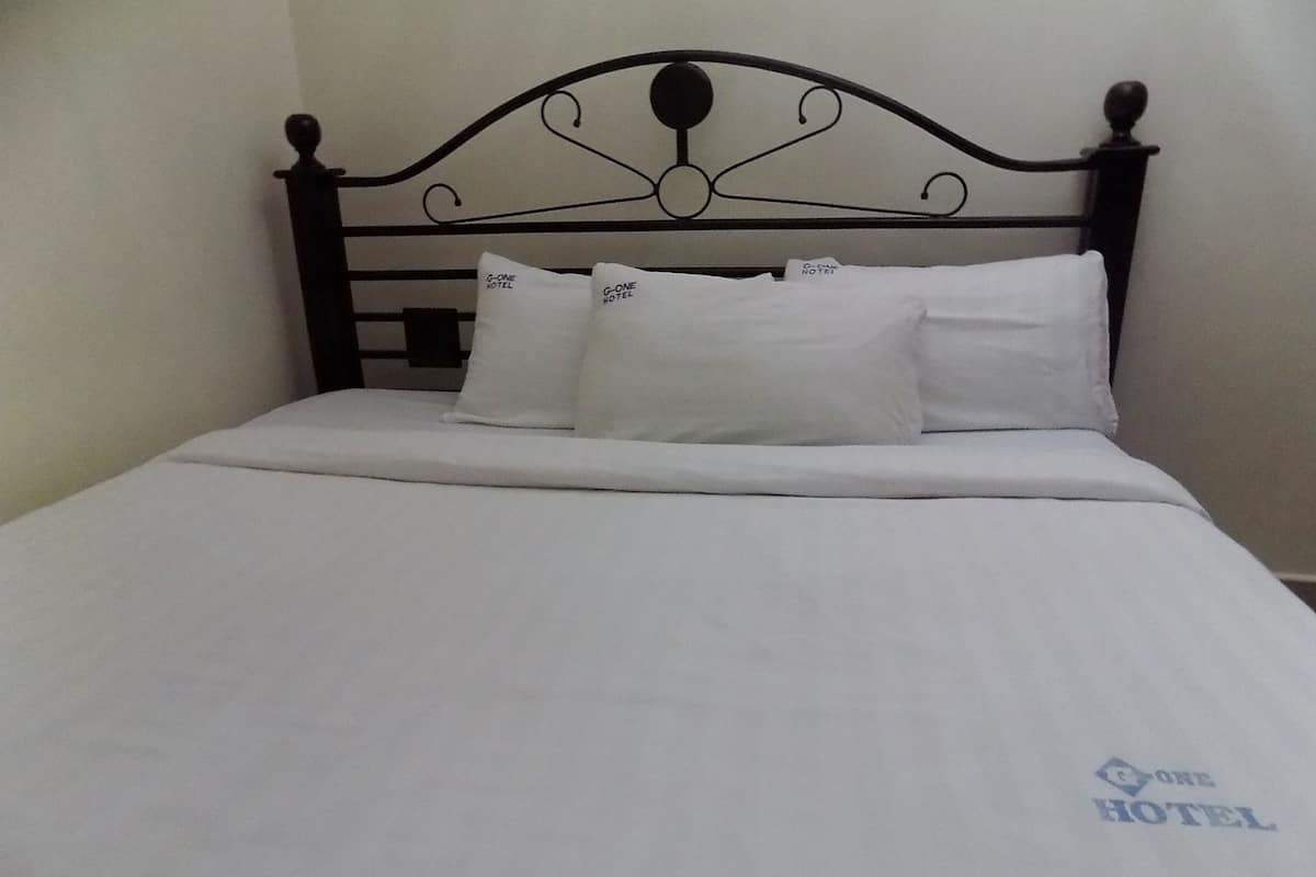 A bed with a black metal headboard, white bedding, and pillows with a hotel logo.