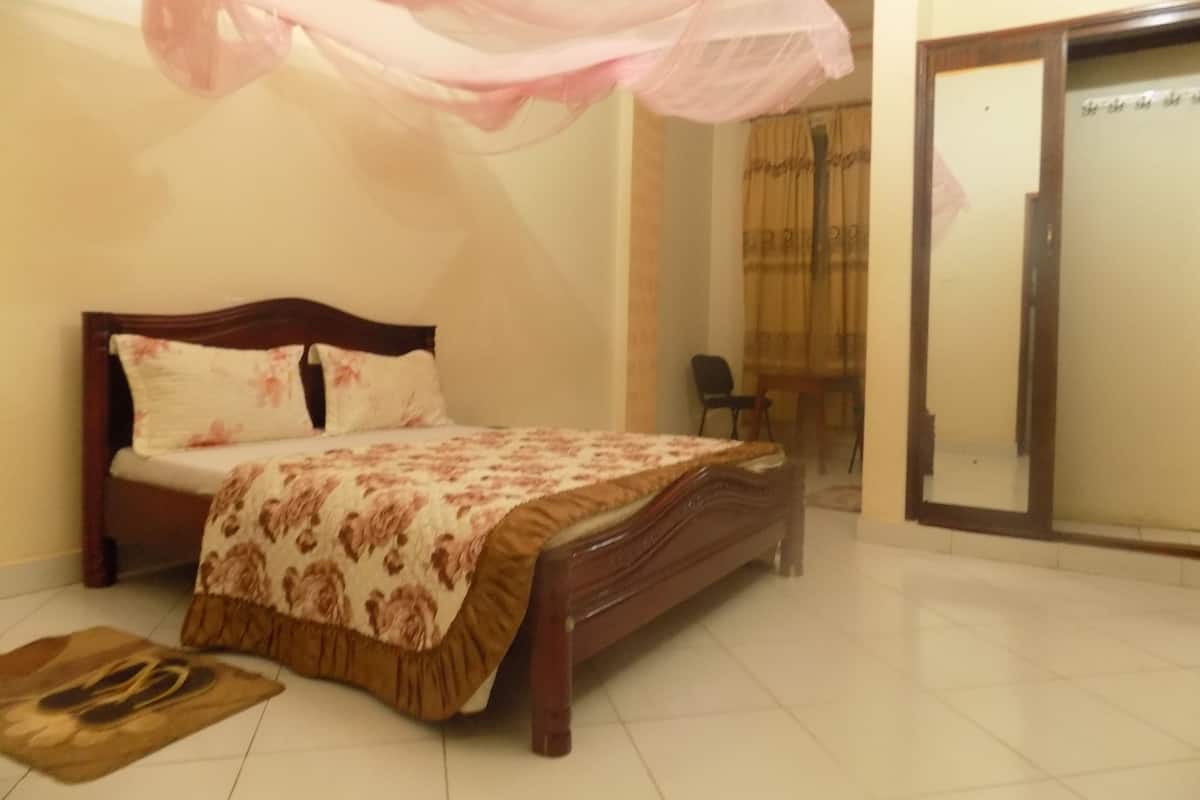 A bedroom with a bed, a chair, and a sliding door.
