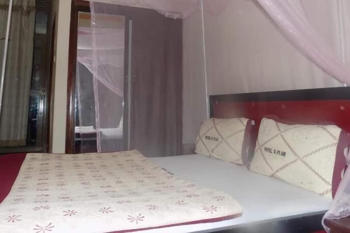 A bed with a canopy, a chair, and a bedspread with a pattern.