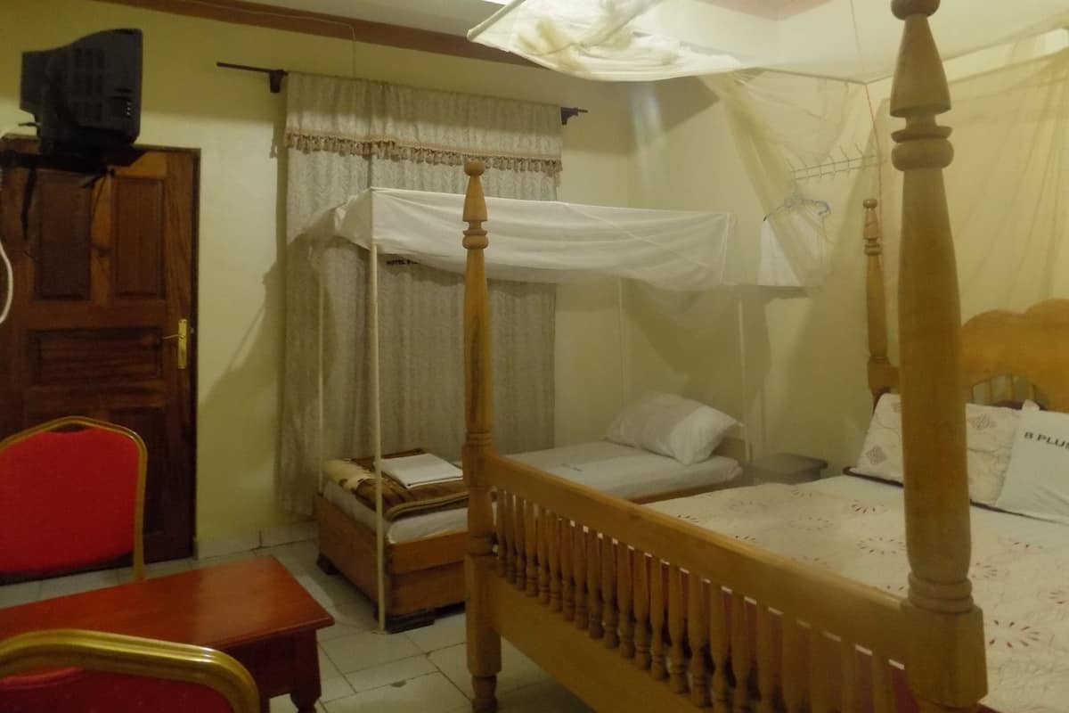 A room with a four-poster bed, a wooden desk, a chair, and a wardrobe.
