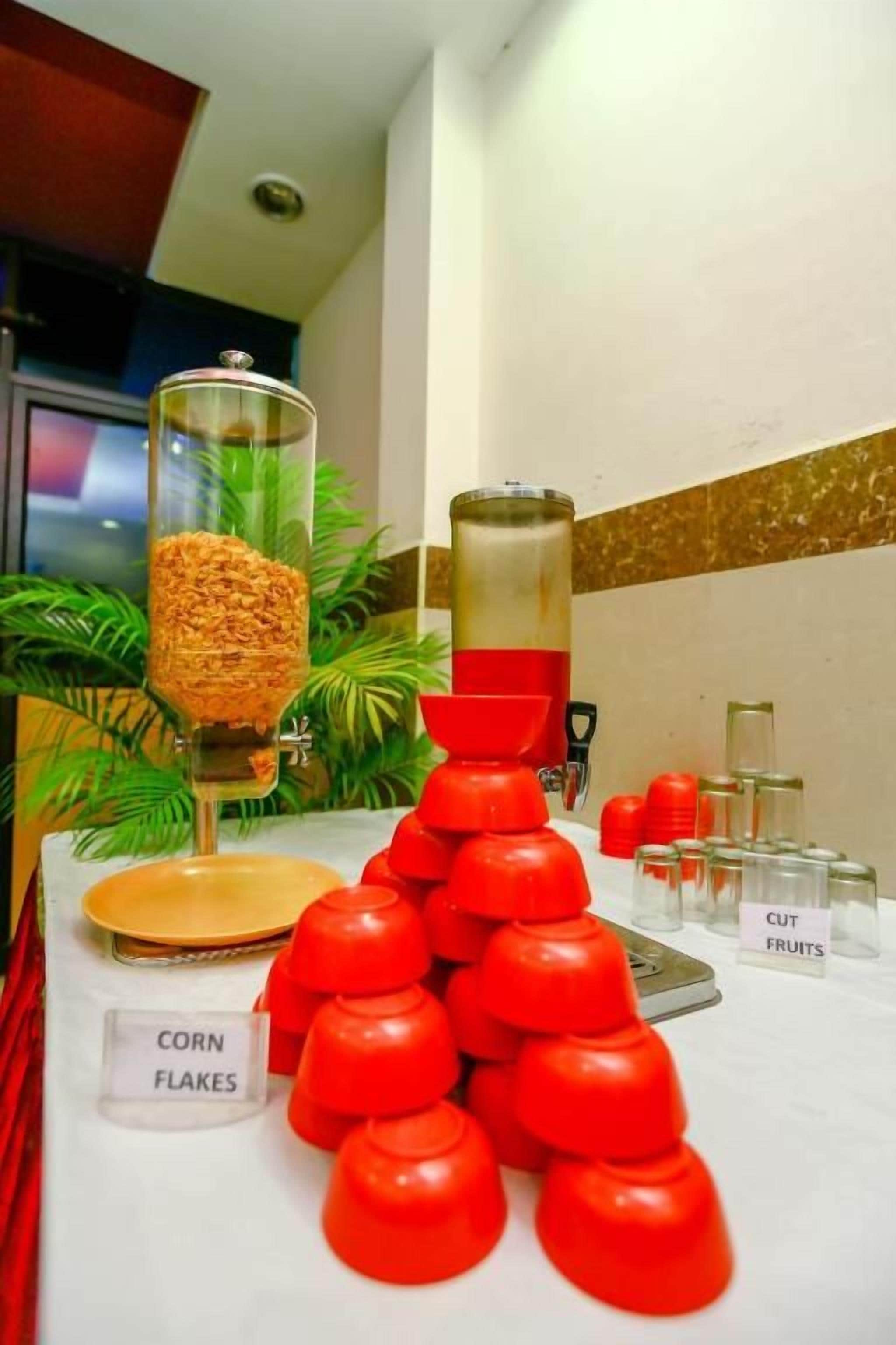 A buffet setup with labeled containers for corn flakes and cut fruits.
