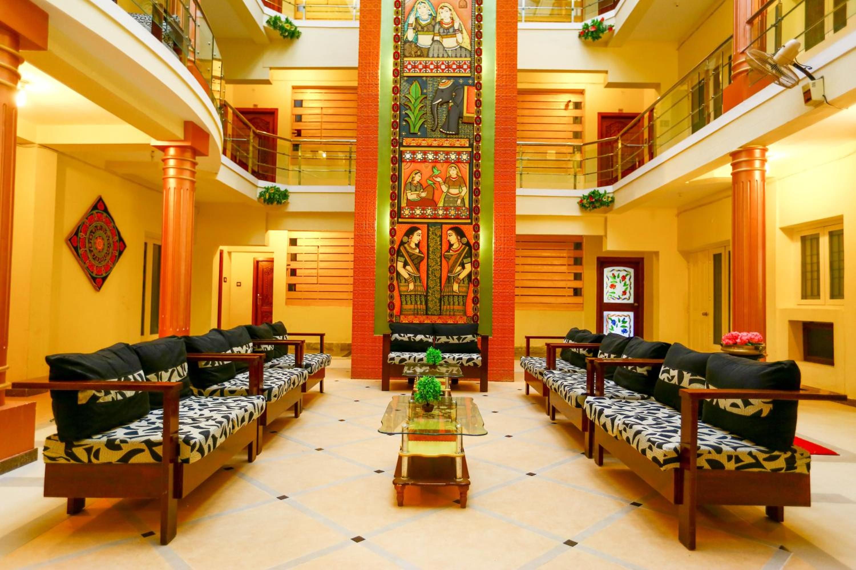 A hotel lobby with a central seating area, two balconies, and a decorative wall.