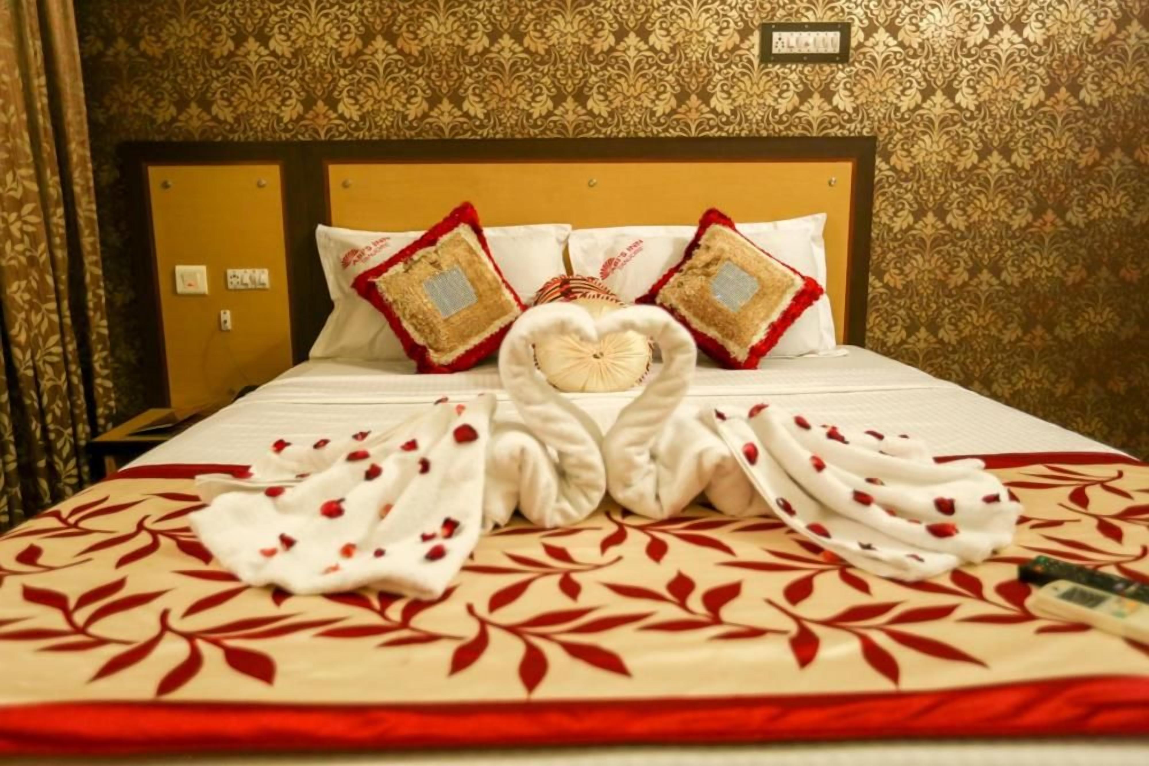 Habitación de hotel con una cama bien hecha, cabecera con un panel decorativo y una pared con papel tapiz estampado.