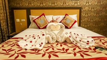 Habitación de hotel con una cama bien hecha, cabecera con un panel decorativo y una pared con papel tapiz estampado.