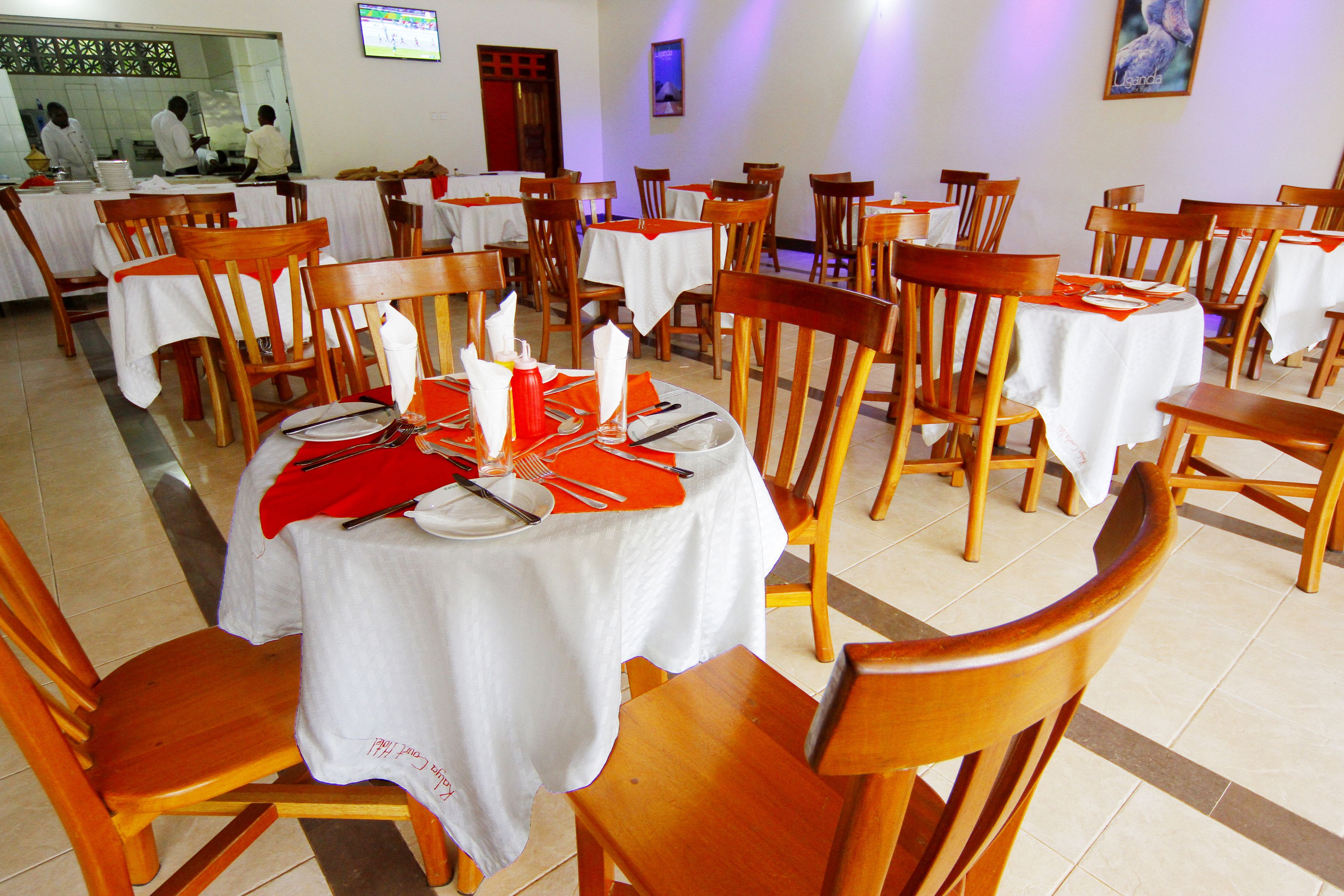 Un ristorante con tavoli rotondi, sedie in legno e tovaglie bianche.