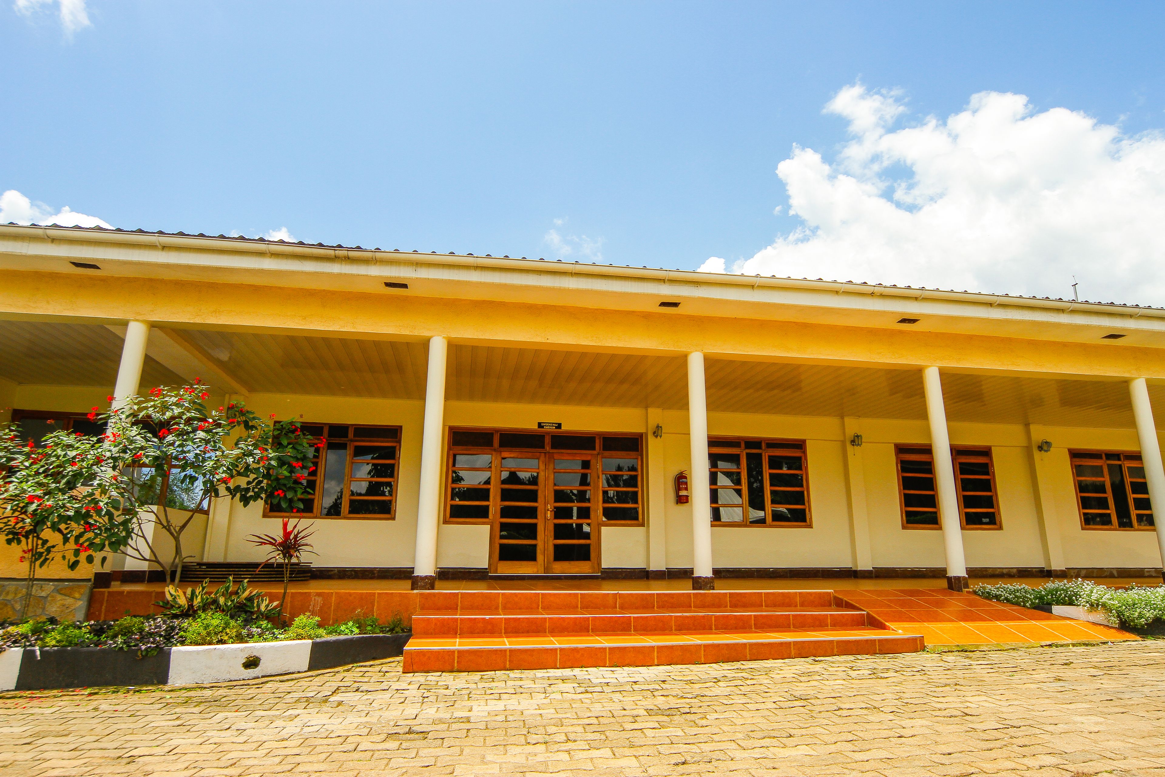 A building with a covered entrance, large windows, and a tiled ground.