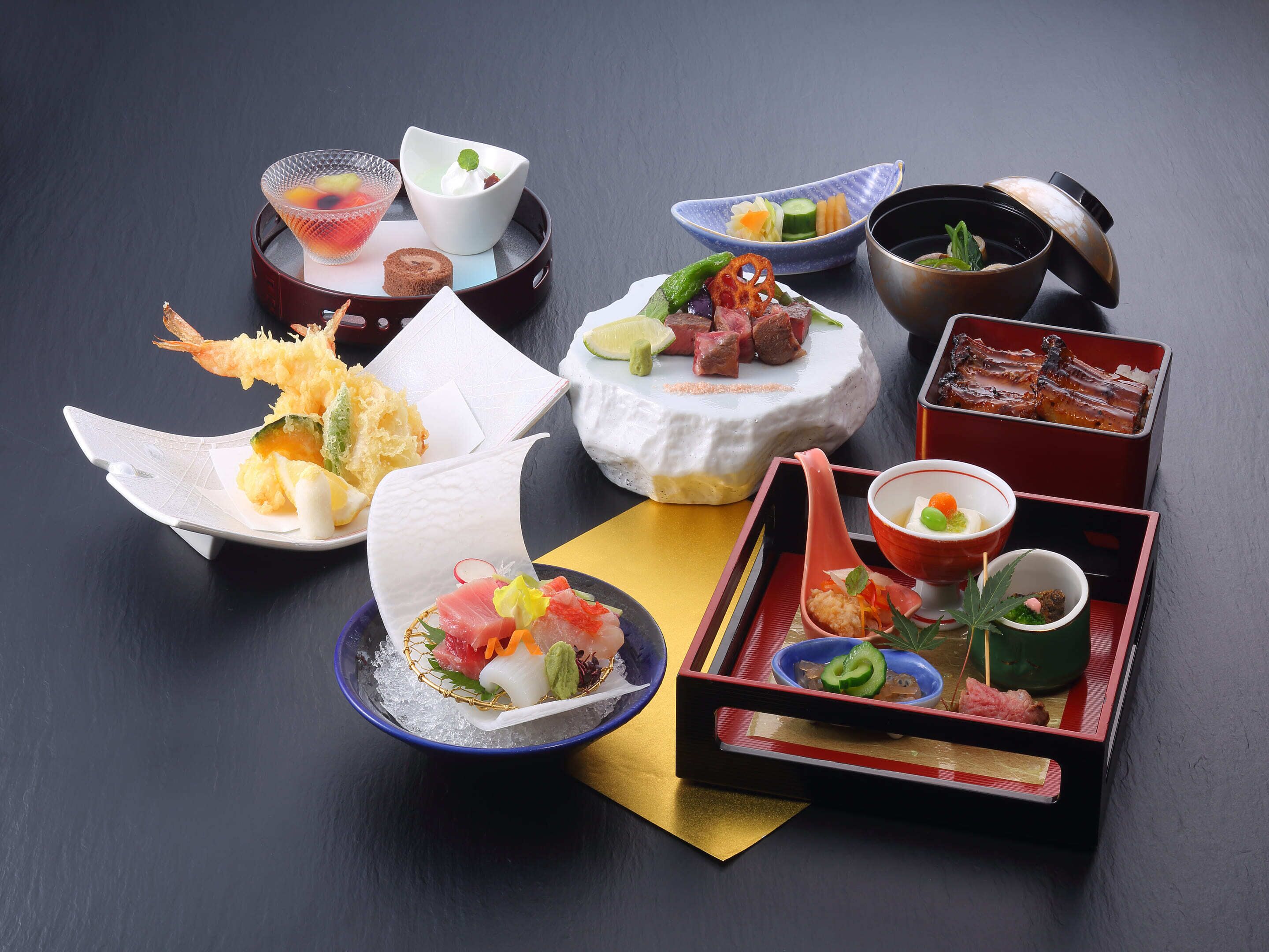 A variety of Japanese dishes arranged on a table, including sushi, sashimi, and tempura.
