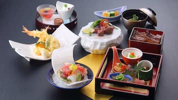 Une variété de plats japonais présentés sur une table, notamment des sushis, des sashimis et des beignets tempura.