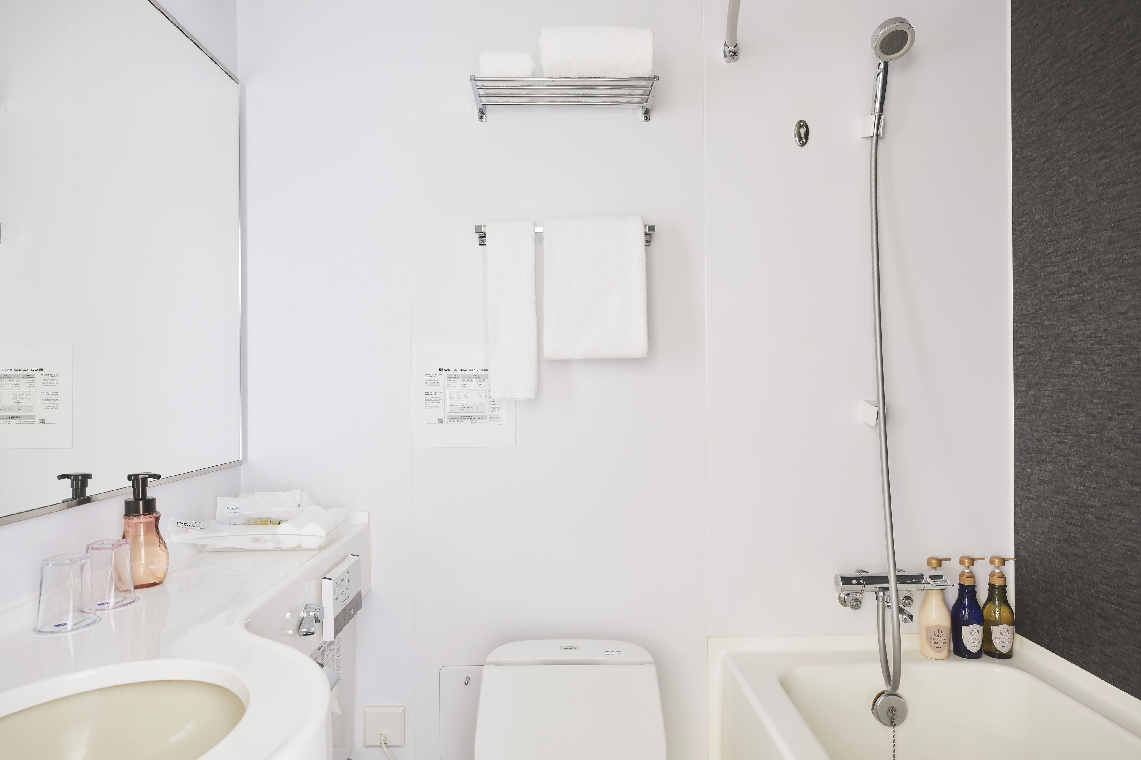 A modern bathroom with a white sink, a toilet, a shower with a handheld showerhead, and a towel rack.