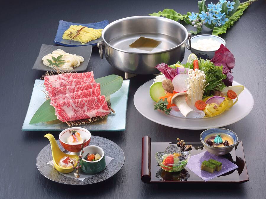 A variety of food items including sashimi, vegetables, and small dishes, arranged on a dark surface.