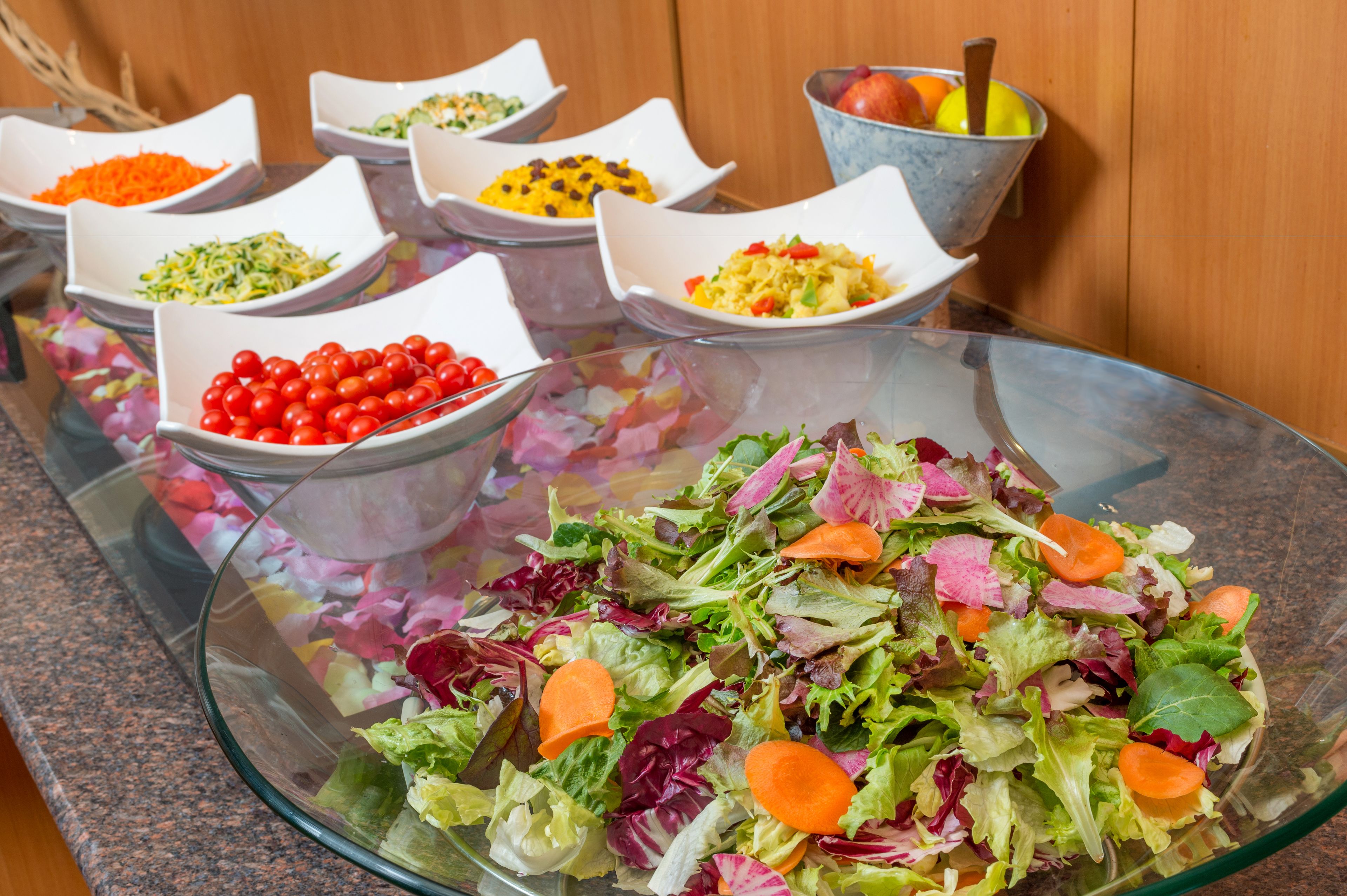 Une table de buffet proposant divers plats, notamment des salades, des fruits et des légumes.