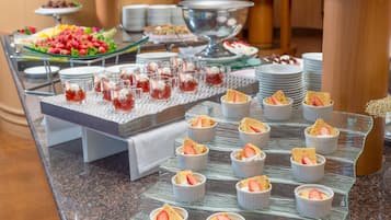 A buffet with various food items including fruit, desserts, and a salad.
