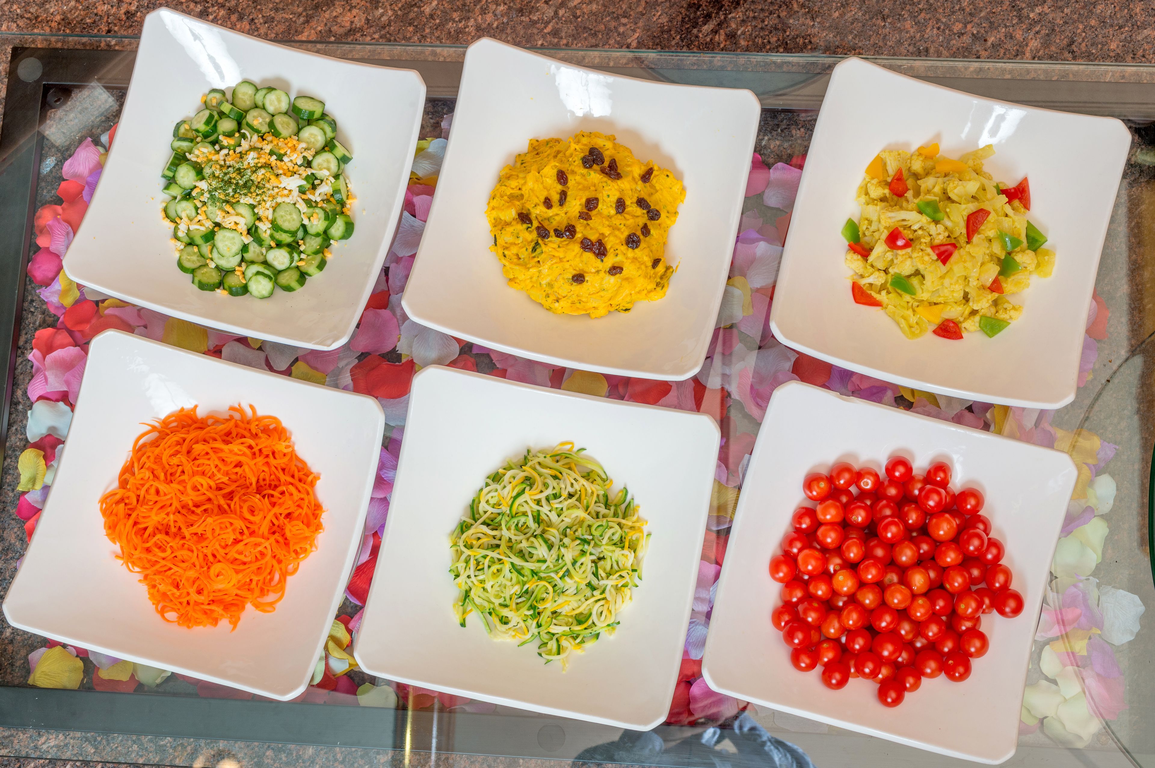 Five square plates with different food items on a table.