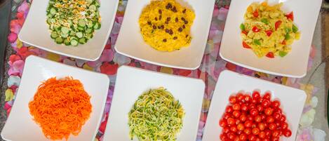 Five square plates with different food items on a table.