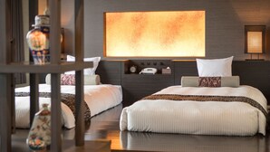 Une chambre d’hôtel moderne avec deux lits, un grand lampadaire fixé au mur et une table de chevet avec un téléphone et une petite horloge.