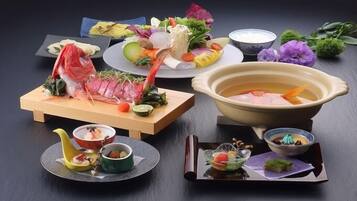 A variety of Japanese dishes including sashimi, vegetables, and a bowl of soup.