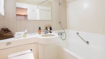 A modern bathroom with a white sink, a bathtub, and a mirror above the sink. There are toiletries on the counter and a towel rack.