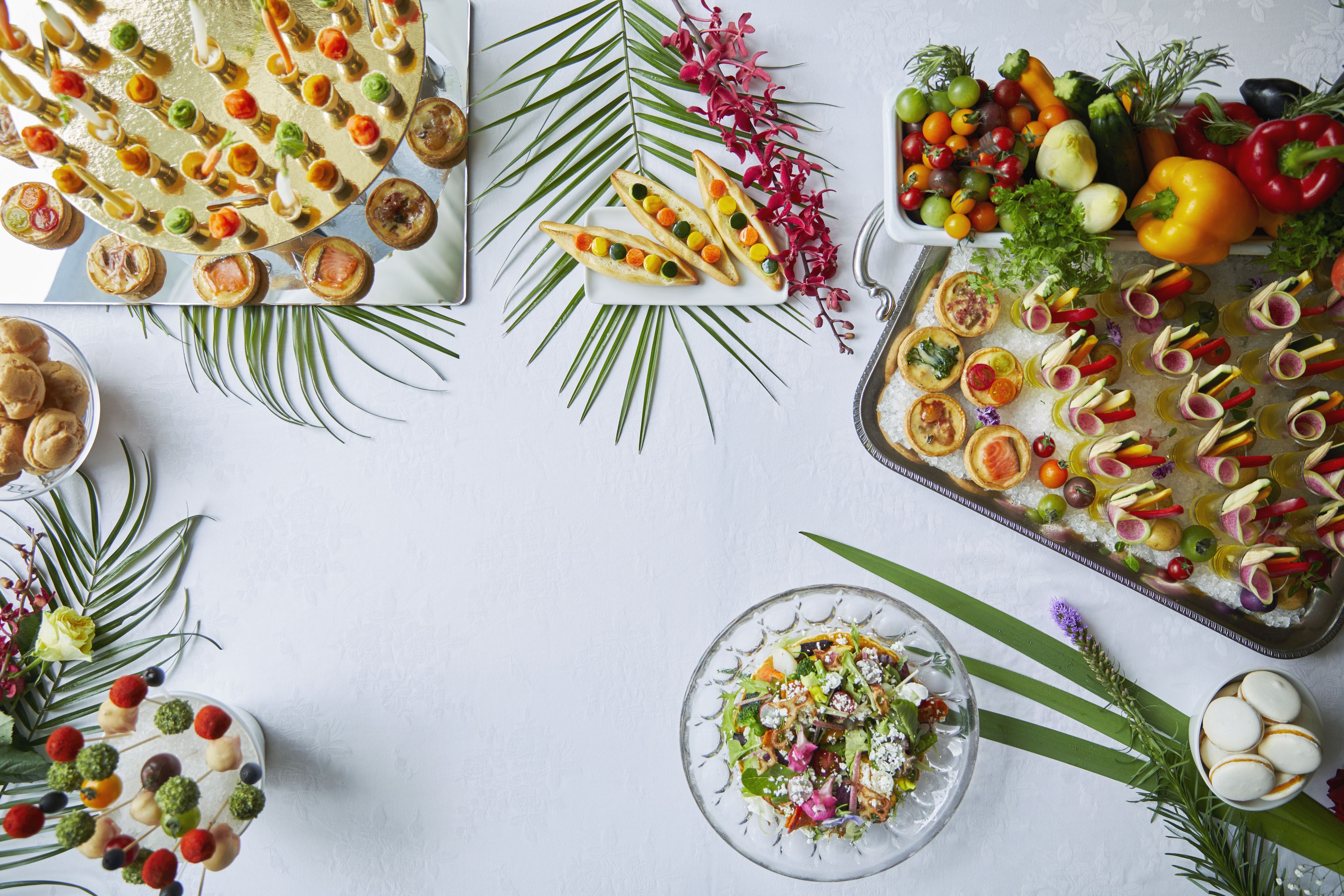 A table with various food items and decorations, including a tray of appetizers, a bowl of salad, and a plate of fruit.