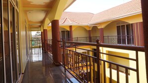 A corridor with a balcony, yellow walls, and a tiled roof. - Oasis Top Hotel (Kampala)