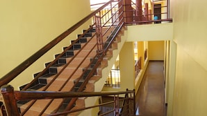 A multi-level interior with a staircase featuring wooden railings and black and brown steps. - Oasis Top Hotel (Kampala)