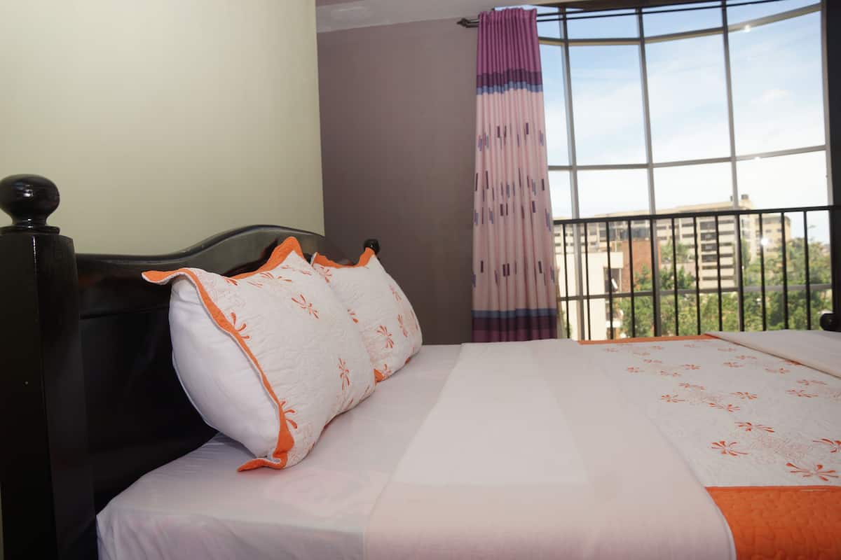 A bedroom with a bed, a window with a view, and a curtain.