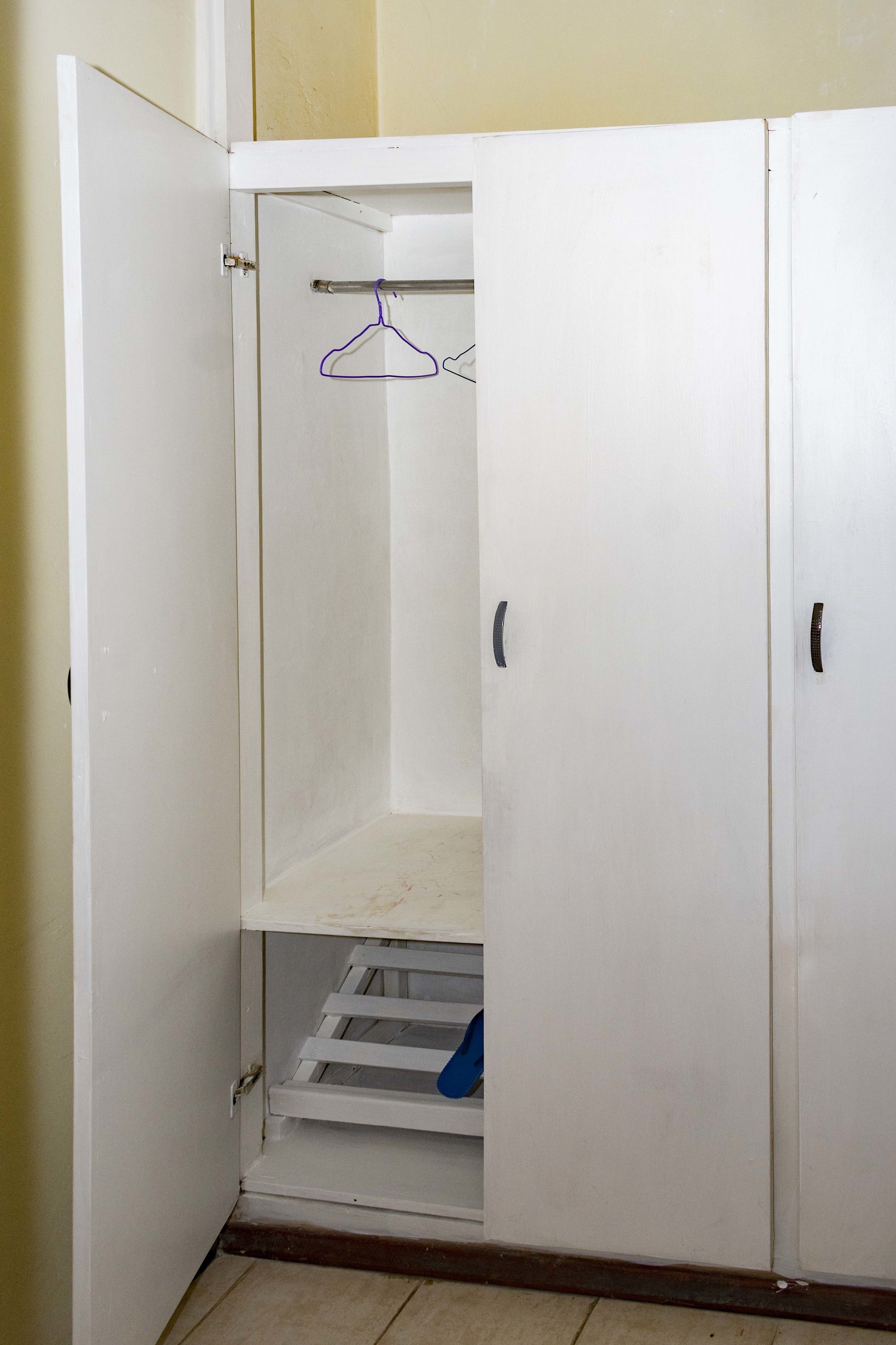 A white wardrobe with a hanging rod and a shelf.