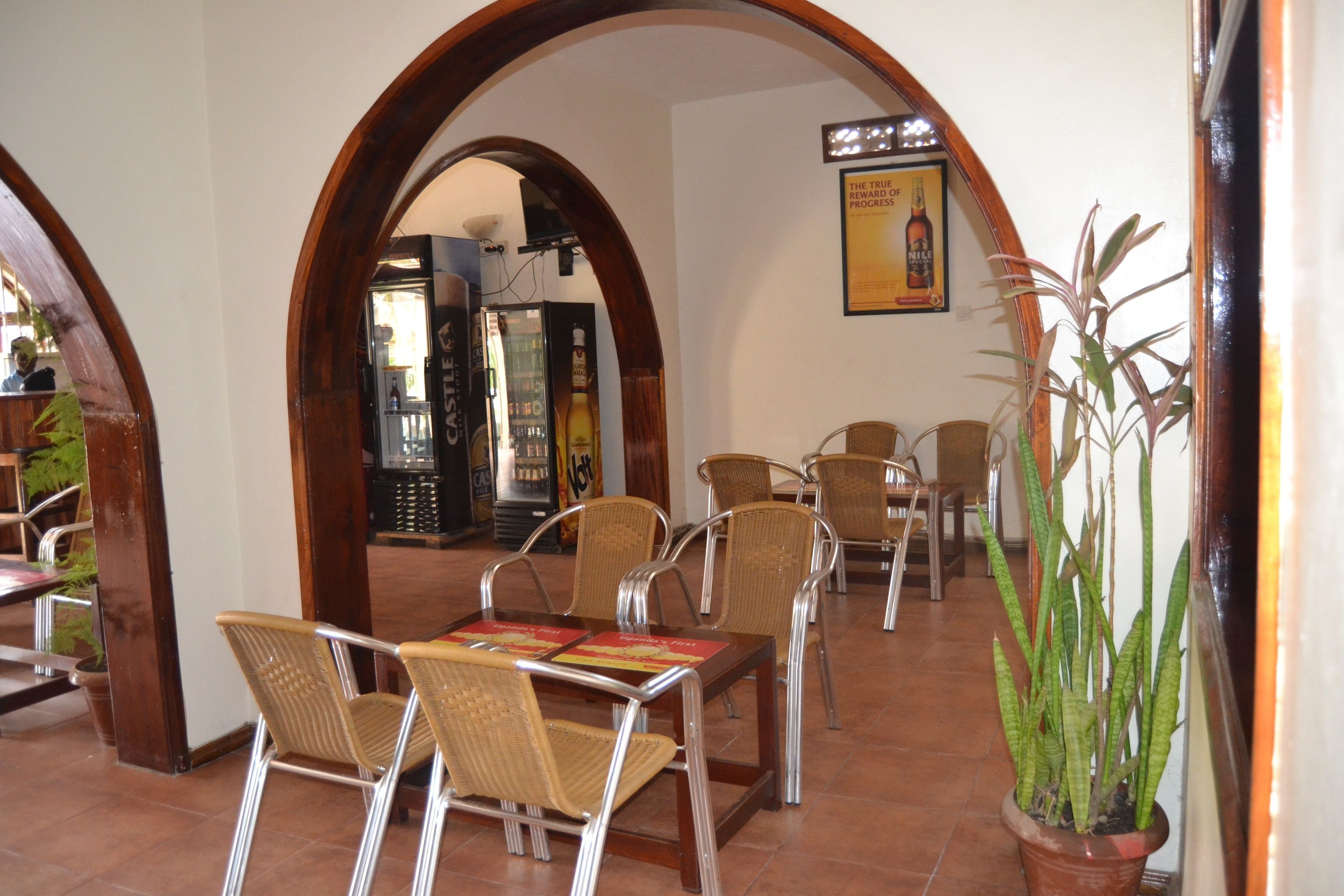 A restaurant with a wooden archway, wicker chairs, and a potted plant.