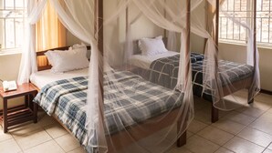 Una cama con dosel, dos mesitas de noche y un teléfono a la izquierda.