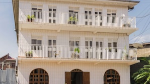 Un edificio de dos plantas con balcones, ventanas arqueadas y plantas en macetas.