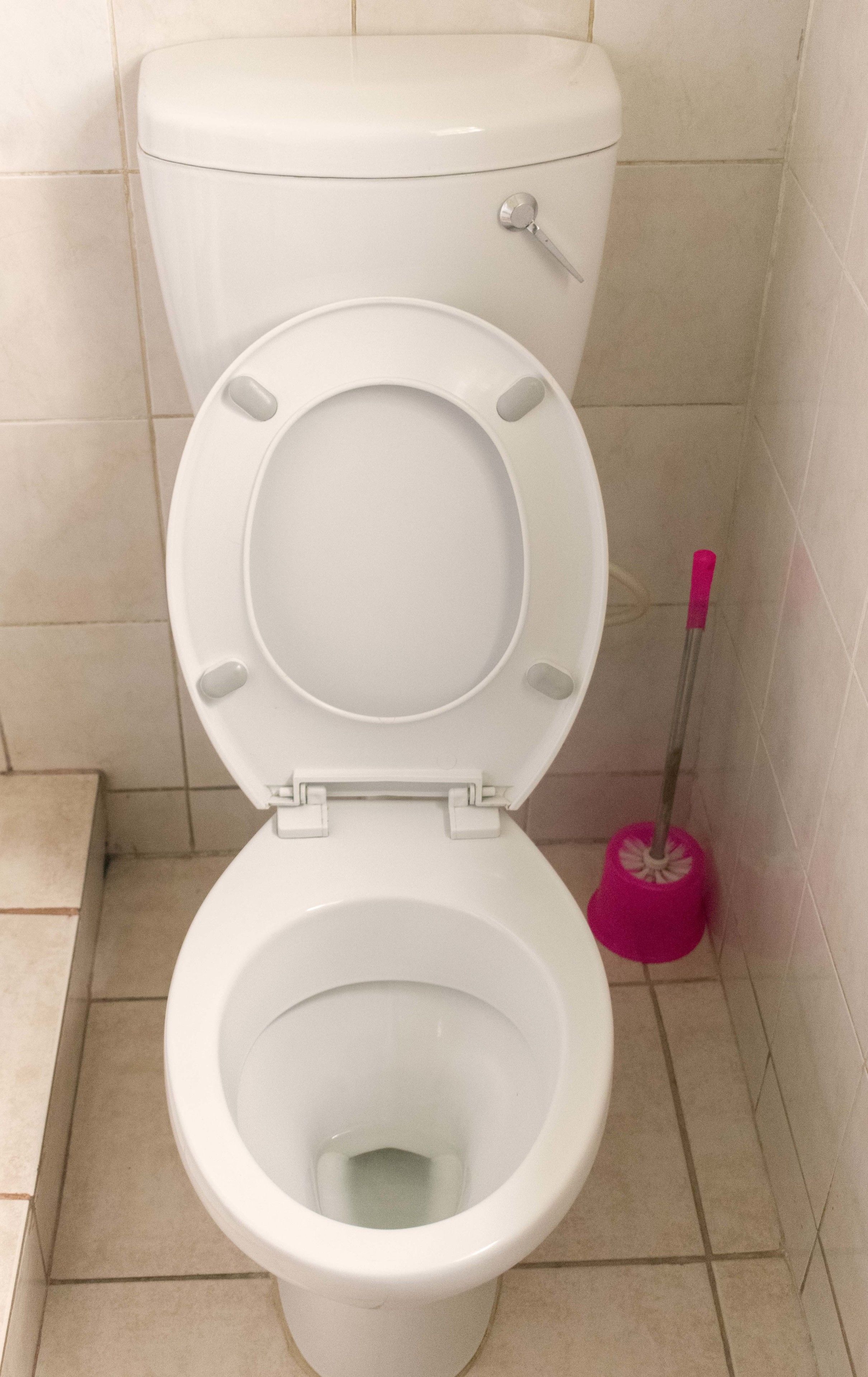 A white toilet with a closed seat in a bathroom with tiled walls and floor.